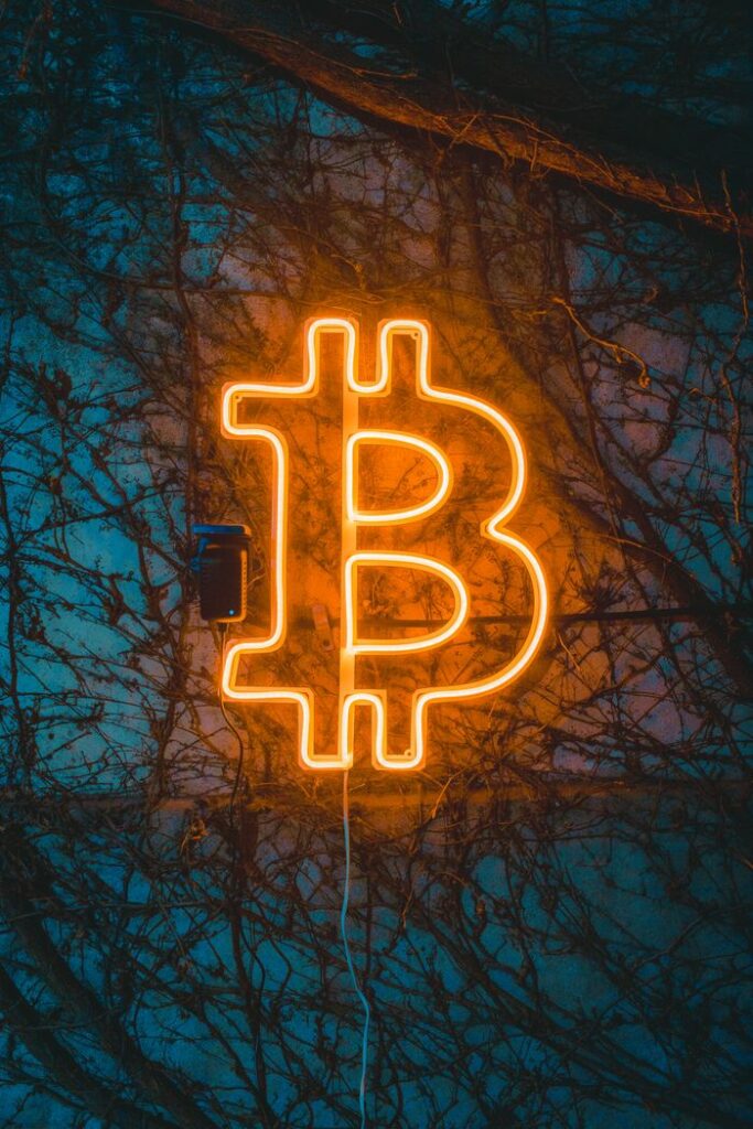 A glowing Bitcoin neon sign adds ambiance against a textured wall, ideal for cryptocurrency themes.