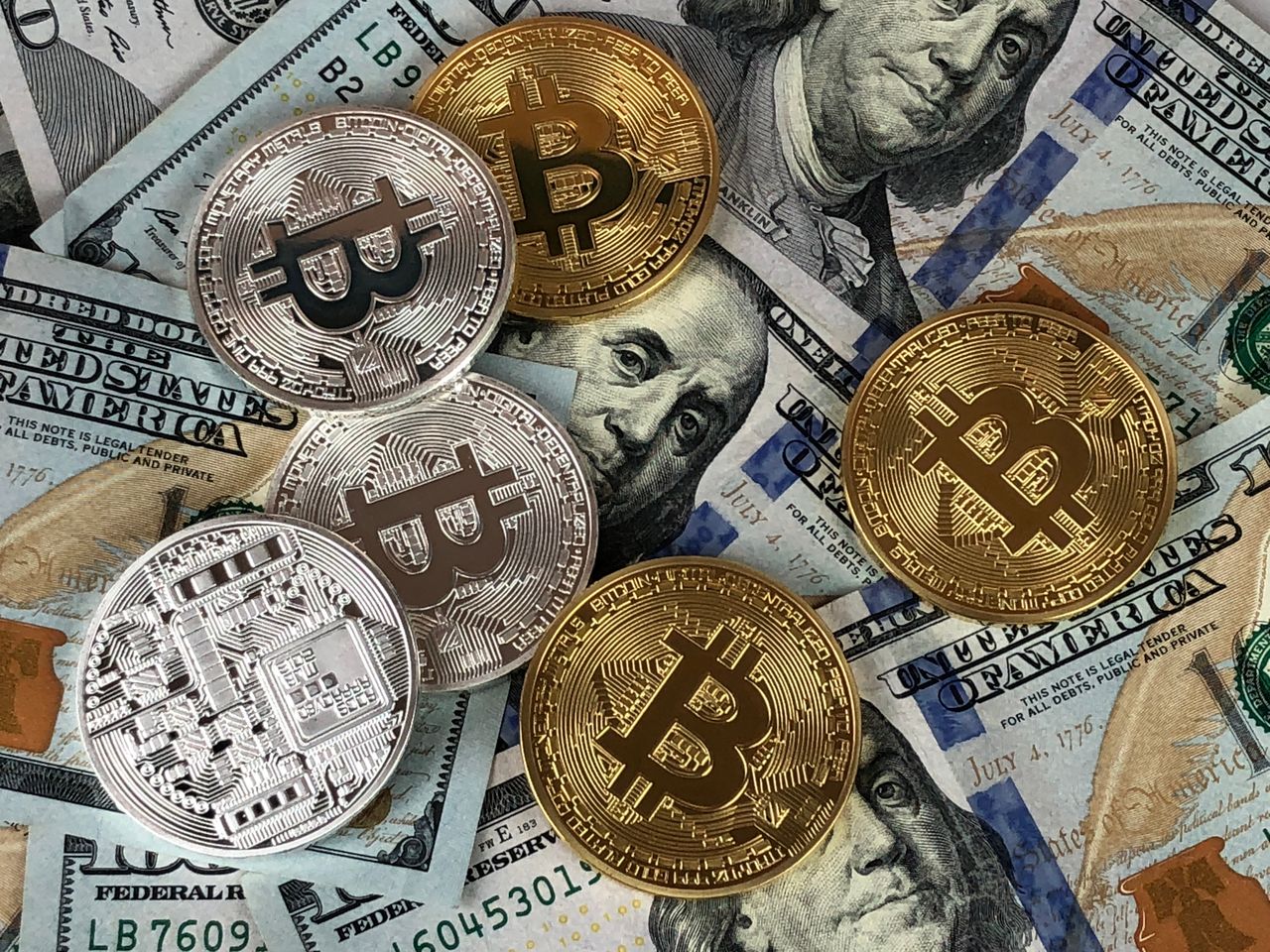 Eyeglasses, smartphone with stock graph, and gold bitcoin coins on a table.